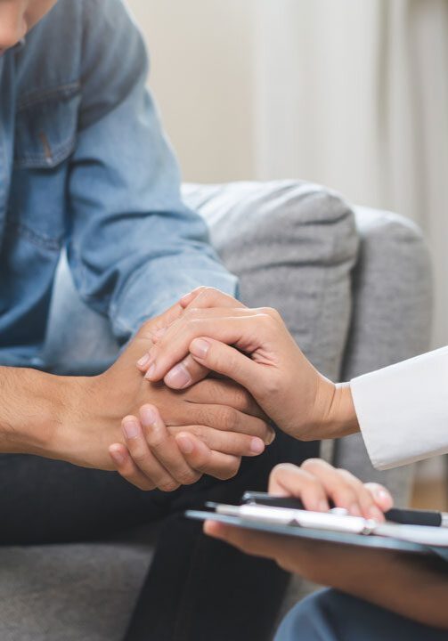 man sitting with head down at grief counseling session