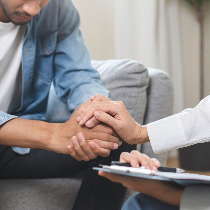 man sitting with head down at grief counseling session
